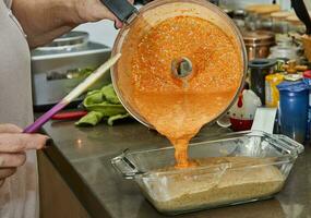 cocinero vierte el masa para haciendo cazuela desde berenjena y calabacín en dos colores dentro el molde foto