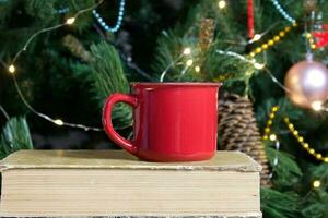 Blank red mug with christmas tree on background,tea or coffee cup with christmas and new year decoration,vertical mock up with ceramic mug for hot drinks,empty gift print template. photo