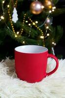 Blank red mug with christmas tree on background,mat tea or coffee cup with christmas and new year decoration,horizontal mock up with ceramic mug for hot drinks,empty gift print template photo