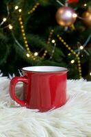 Blank red mug with christmas tree on background,mat tea or coffee cup with christmas and new year decoration,vertical mock up with ceramic mug for hot drinks,empty gift print template photo