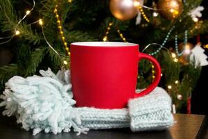 Blank red mug with christmas tree on background,mat tea or coffee cup with christmas and new year decoration,vertical mock up with ceramic mug for hot drinks,empty gift print template photo