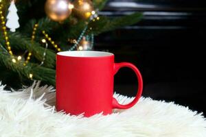 Blank red mug with christmas tree on background,mat tea or coffee cup with christmas and new year decoration,horizontal mock up with ceramic mug for hot drinks,empty gift print template photo