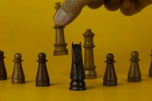 Hand holding Realistic queen on bright yellow background with copy space. Chess piece. Minimal creative battle concept photo