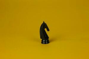 un negro caballo ajedrez en pie para frente a a problema en negocio en aislado amarillo fondo, usado para éxito y estrategia concepto foto