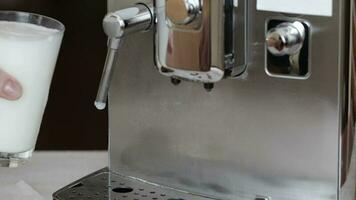 Glass of milk close to the coffee maker. Closeup video