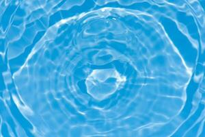 Blue water with ripples on the surface. Defocus blurred transparent blue colored clear calm water surface texture with splashes and bubbles. Water waves with shining pattern texture background. photo