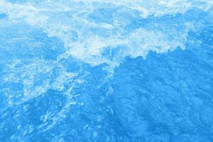 Blue water with ripples on the surface. Defocus blurred transparent blue colored clear calm water surface texture with splashes and bubbles. Water waves with shining pattern texture background. photo