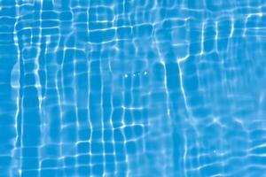 Blue water with ripples on the surface. Defocus blurred transparent blue colored clear calm water surface texture with splashes and bubbles. Water waves with shining pattern texture background. photo