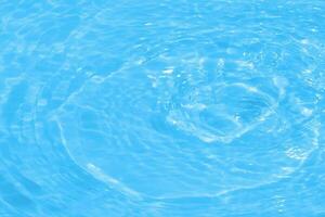 Blue water with ripples on the surface. Defocus blurred transparent blue colored clear calm water surface texture with splashes and bubbles. Water waves with shining pattern texture background. photo