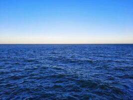 Blue sky and ocean with ripples on the surface. Defocus blurred transparent blue sea surface texture with splashes and bubbles. Water waves with shining pattern texture background. photo