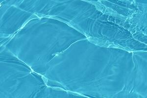 azul agua con ondas en el superficie. desenfocar borroso transparente azul de colores claro calma agua superficie textura con salpicaduras y burbujas agua olas con brillante modelo textura antecedentes. foto