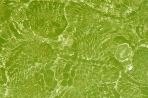 Light green water with ripples on the surface. Defocus blurred transparent colored clear calm water surface texture with splashes and bubbles. Water waves with shining pattern texture background. photo