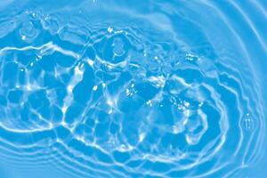 Blue water with ripples on the surface. Defocus blurred transparent blue colored clear calm water surface texture with splashes and bubbles. Water waves with shining pattern texture background. photo