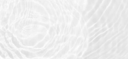 White water with ripples on the surface. Defocus blurred transparent white colored clear calm water surface texture with splashes and bubbles. Water waves with shining pattern texture background. photo