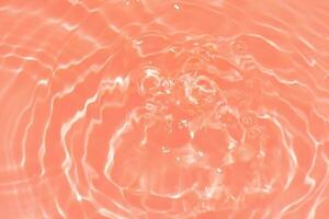 Orange water with ripples on the surface. Defocus blurred transparent pink colored clear calm water surface texture with splashes and bubbles. Water waves with shining pattern texture background. photo