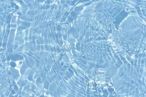 Blue water with ripples on the surface. Defocus blurred transparent blue colored clear calm water surface texture with splashes and bubbles. Water waves with shining pattern texture background. photo