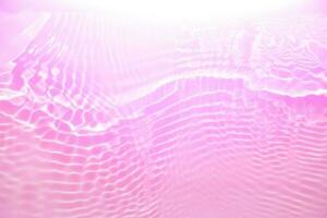 Purple water with ripples on the surface. Defocus blurred transparent pink colored clear calm water surface texture with splashes and bubbles. Water waves with shining pattern texture background photo