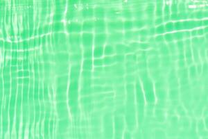 Green water with ripples on the surface. Defocus blurred transparent blue colored clear calm water surface texture with splashes and bubbles. Water waves with shining pattern texture background. photo
