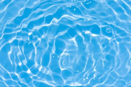 Blue water with ripples on the surface. Defocus blurred transparent blue colored clear calm water surface texture with splashes and bubbles. Water waves with shining pattern texture background. photo