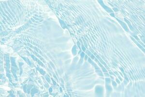 Blue water with ripples on the surface. Defocus blurred transparent blue colored clear calm water surface texture with splashes and bubbles. Water waves with shining pattern texture background. photo