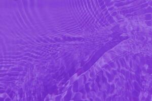 Purple water with ripples on the surface. Defocus blurred transparent pink colored clear calm water surface texture with splashes and bubbles. Water waves with shining pattern texture background. photo