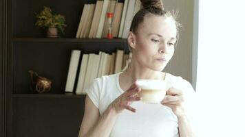 Young lady is in her office at home drinking coffee while look out the window video