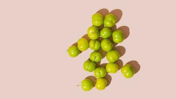 Green fresh raw plums on pink background, copy space, mockup, isolated photo