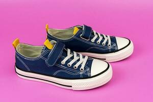 a pair of blue sneakers on a pink background. Fashionable youth shoes photo