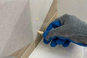 worker's hand inserts a plastic dowel pin into a drilled hole photo
