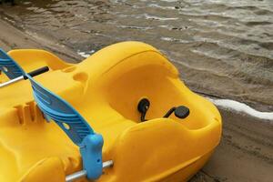 Funny colored plastic catamaran on the lake shore. Summer holidays photo