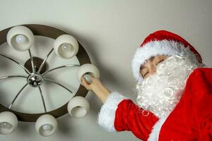 Santa changes the burned-out light bulbs in the chandelier photo