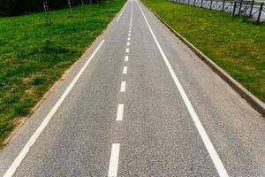 un vacío ciudad bicicleta camino a lo largo un ciudad calle en verano foto