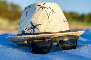 sun hat and sunglasses on a beach blanket. concept of summer holidays photo