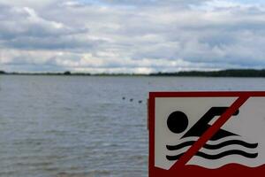 eso es prohibido a nadar firmar instalado en el apuntalar de el lago foto