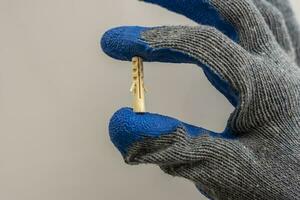 A worker 's hand in a protective glove holds a plastic dowel pin photo