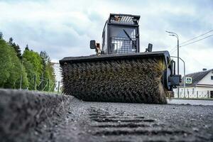 Cleaning of garbage from the road. a rotating mechanical machine brush photo