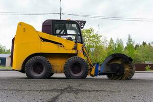 Cleaning of garbage from the road. a rotating mechanical machine brush photo