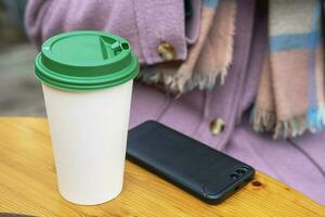 close-up of hot coffee in a paper cup on a table in an outdoor cafe photo