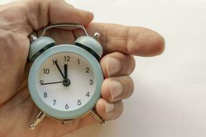 close-up of a small blue alarm clock in man's hand. the time is 23-55 photo