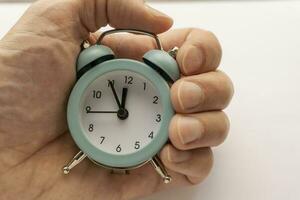 close-up of a small blue alarm clock in man's hand. the time is 23-55 photo
