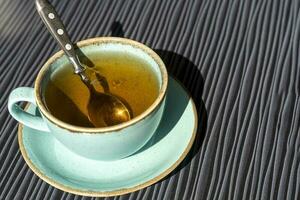 turquoise cup of hot tea on a table in the sunlight during breakfast photo