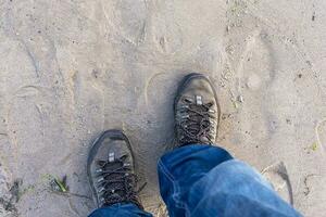 man in boots and blue jeans walks along the wet sand of the sea beach photo