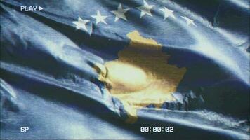 VHS video casette record Kosovo flag waving on the wind. Glitch noise with time counter recording Kosovsky banner swaying on the breeze. Seamless loop.