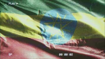 VHS video casette record Ethiopia flag waving on the wind. Glitch noise with time counter recording Ethiopian banner swaying on the breeze. Seamless loop.