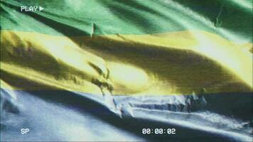 VHS video casette record Gabon flag waving on the wind. Glitch noise with time counter recording Gabonese banner swaying on the breeze. Seamless loop.