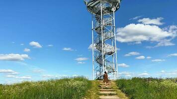 mulher turista de espiral Escadaria do tenha cuidado torre, construção com metal passos. observação torre, postar ou ponto. siberija observação área coberta torre video