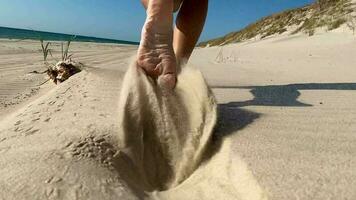 långsam rörelse makro oigenkännlig kvinna löpning i varm sommar Sol längs de solig exotisk Strand i curonian spotta sandig kustlinje.bekymmerslös flicka tar av henne flip flops och kör video