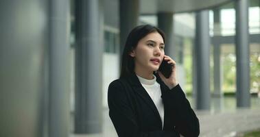 Young Asian businesswoman in suit talking on  smartphone at modern office photo