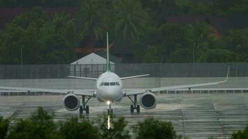 Passenger plane rides across the airfield, rain. The rainy season in Phuket, Thailand. Tourism and travel concept video