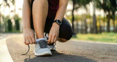 Primer plano del corredor de la mujer joven atando sus cordones. concepto de salud y fitness. foto